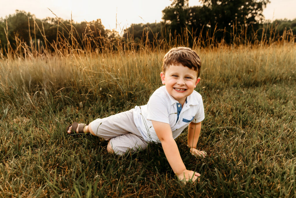 Little boy grinning as he crawls through the grass