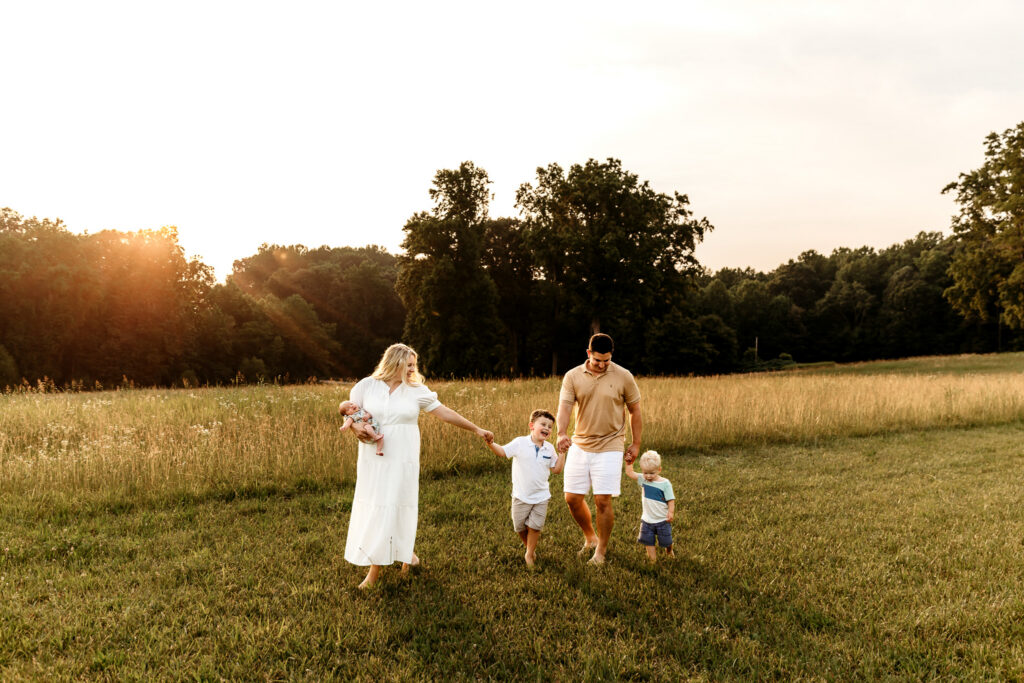 Family of five walking through an open field at sunset in Statesville, NC